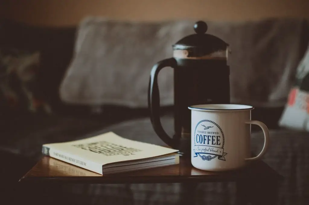 french press with a mug of coffee and a book