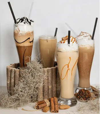 Four iced coffee drinks with whipped cream and cinnamon sticks, including frappuccinos.
