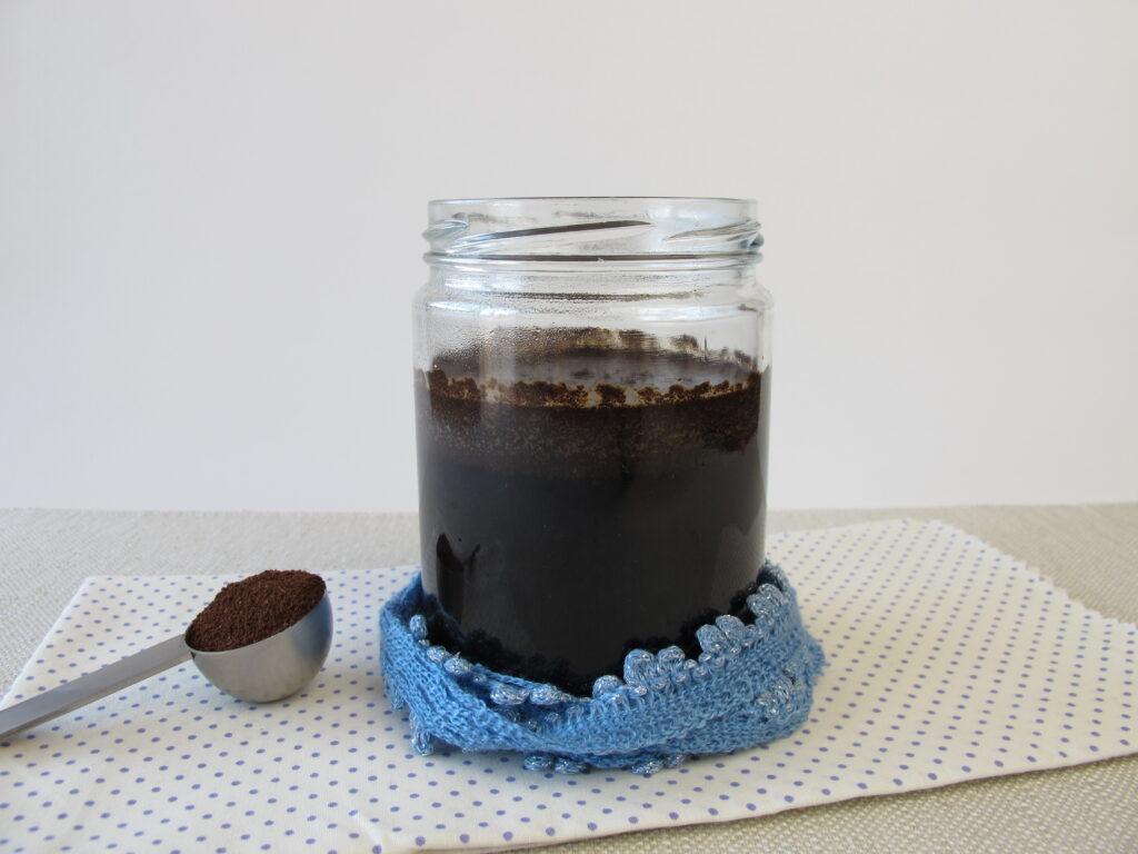 Glass jar containing coffee and water for making cold brew coffee.