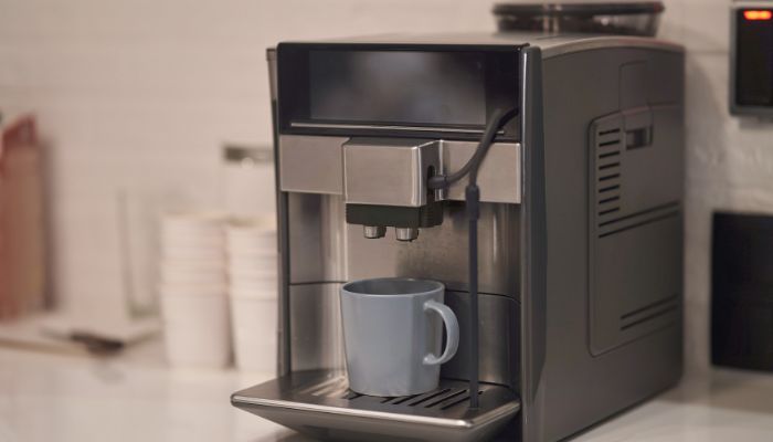 A modern coffee machine dispensing coffee into a light blue mug on a counter.