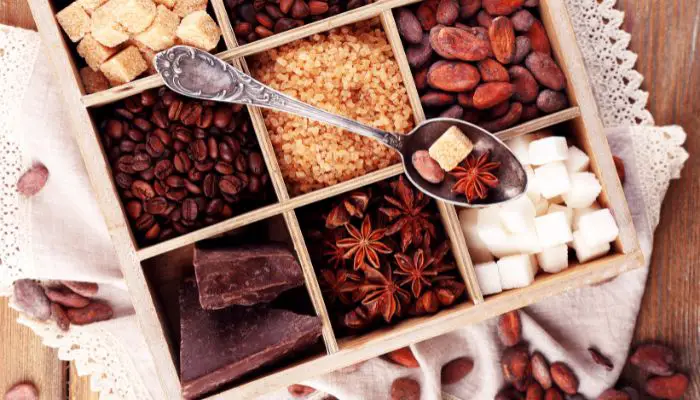Assorted spiced to flavor coffee beans in a wooden compartment box with a spoon.